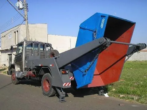 Caminhão poliguindaste transportando caçamba